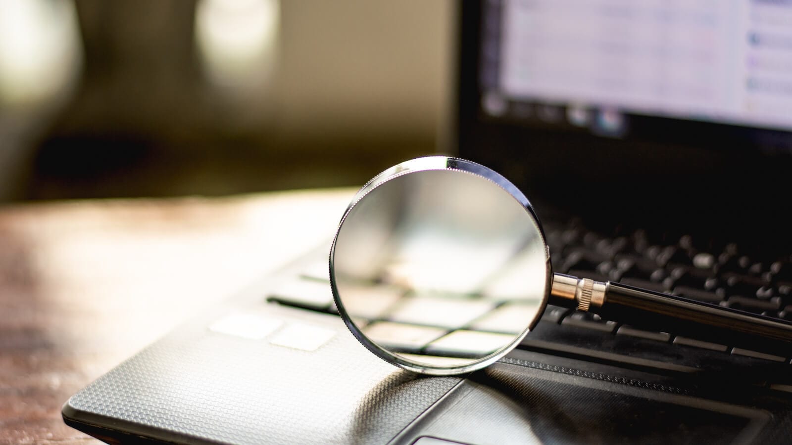 Magnifying glass on laptop implying scanning the stock market