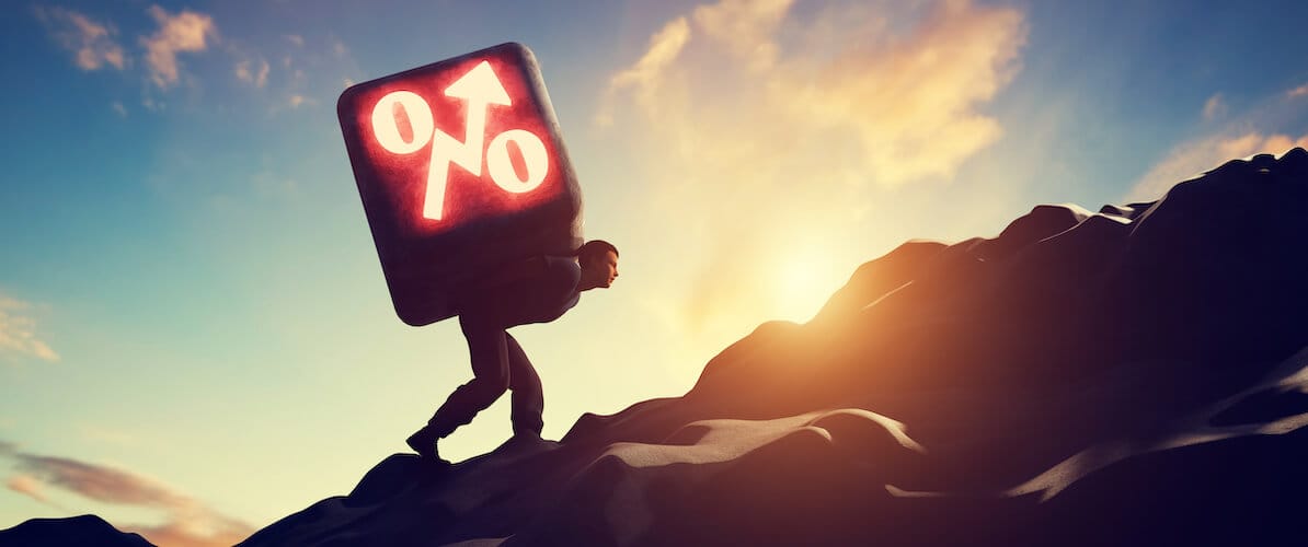 Person going uphill with weight of interest rates on back