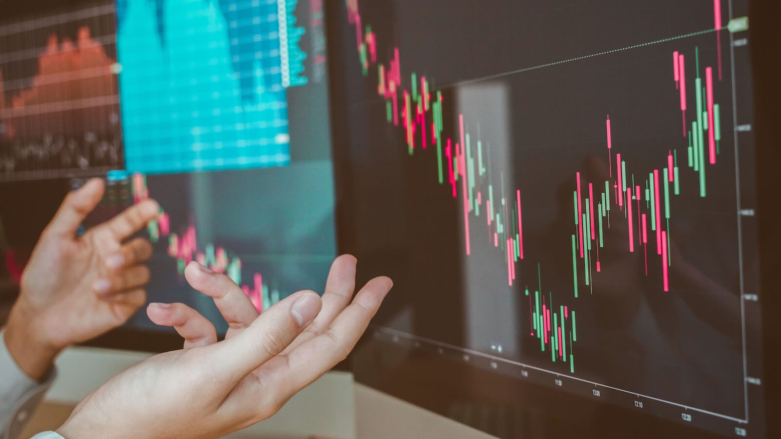 Stock chart on screen, person's hands showing confusion