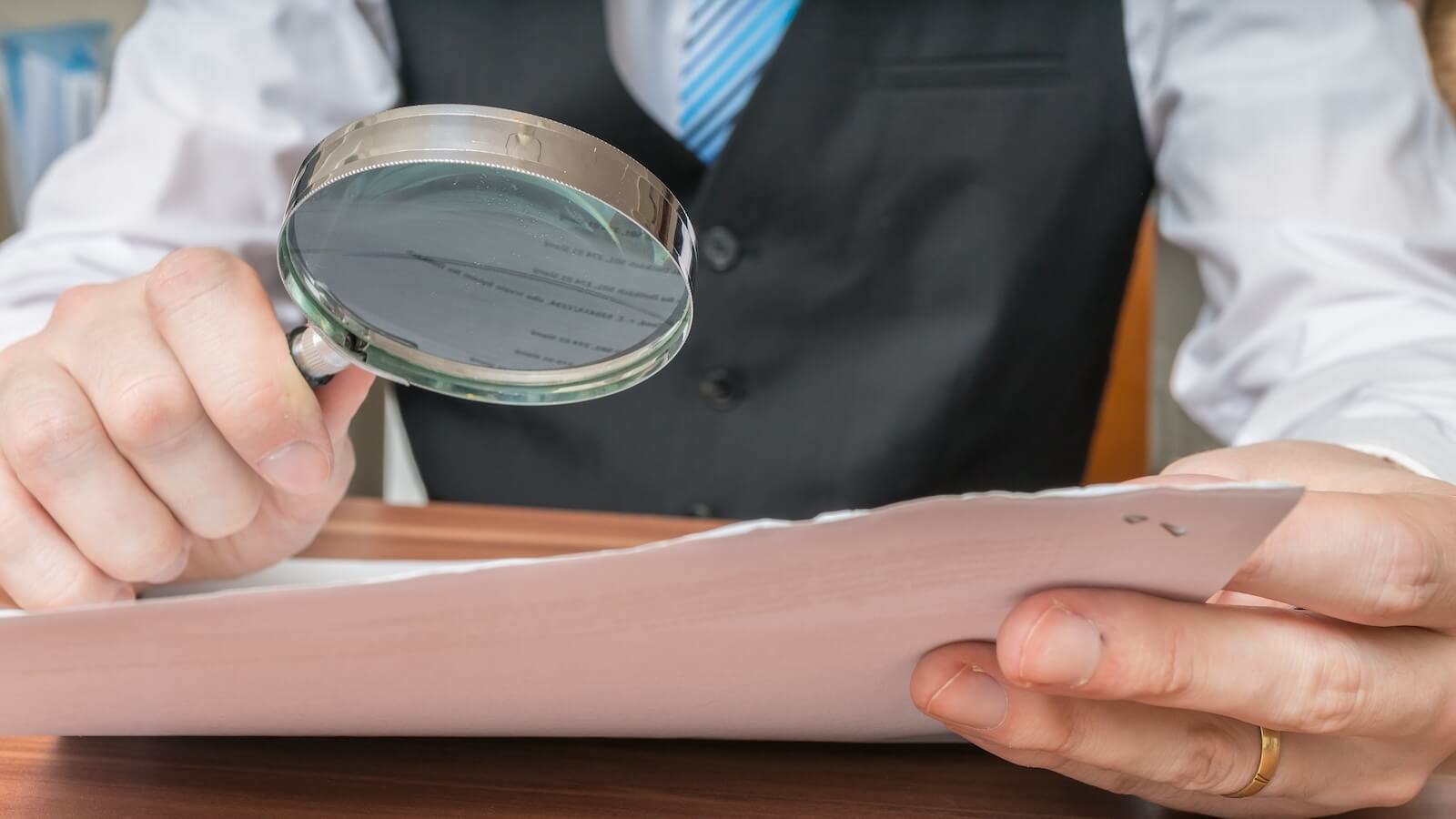 Man using magnifying glass to view document
